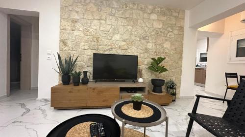 a living room with a flat screen tv on a wooden stand at Marko's Place in Hanioti