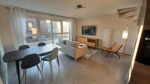 un salon avec une table et un canapé dans l'établissement Le cottage du moulin - NETFLIX - WiFi - Garage, à Oresmaux