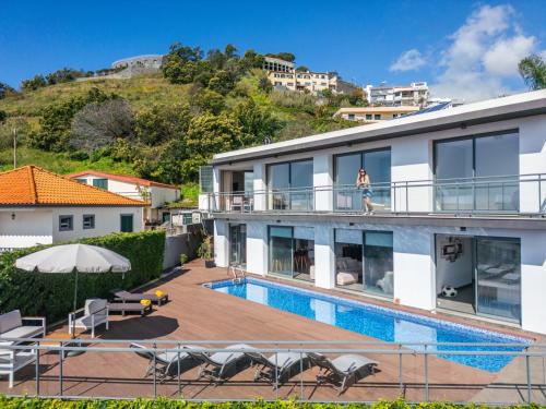 a woman standing on the balcony of a house with a swimming pool at Villa Beausoleil by Homie in Funchal
