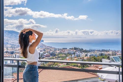 a woman standing on a balcony looking at the city at Villa Beausoleil by Homie in Funchal