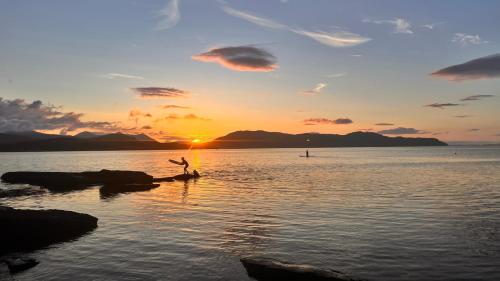 a person jumping off a rock in the water at sunset at Carnmhor, Isle of Skye - Stunning 242 year old cottage on its own sea shore! in Breakish