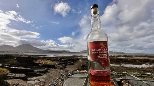 a bottle of alcohol sitting on top of a beach at Carnmhor, Isle of Skye - Stunning 242 year old cottage on its own sea shore! in Breakish
