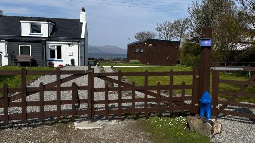 a wooden fence in front of a house at Carnmhor, Isle of Skye - Stunning 242 year old cottage on its own sea shore! in Breakish