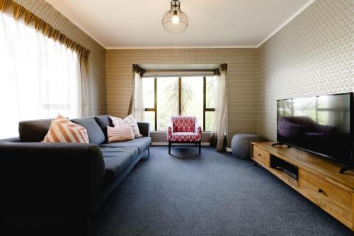 a living room with a couch and a flat screen tv at Comfortable 2BR Home w Free Parking, Easy Walk to City in Wellington