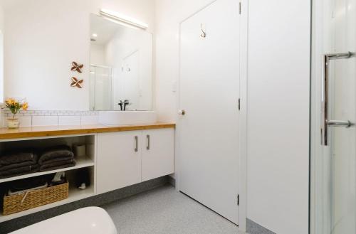 a white bathroom with a sink and a mirror at Comfortable 2BR Home w Free Parking, Easy Walk to City in Wellington