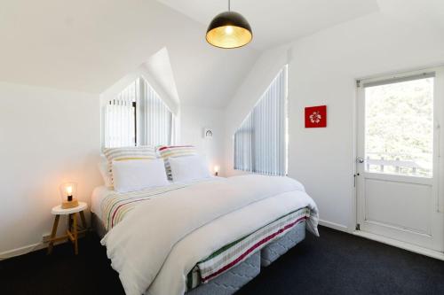 a white bedroom with a large bed and a window at Comfortable 2BR Home w Free Parking, Easy Walk to City in Wellington