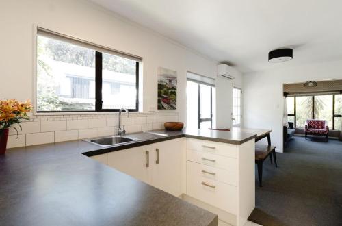 a kitchen with white cabinets and a sink and windows at Comfortable 2BR Home w Free Parking, Easy Walk to City in Wellington