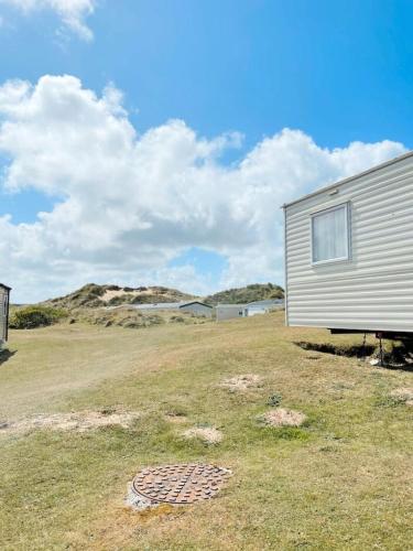 a building in the middle of a field with a house at Ocean Breeze-Haven Perran Sands Holiday Park in Perranporth