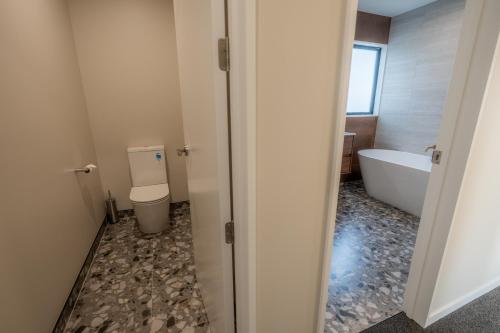 a bathroom with a tub and a toilet and a sink at Serenity Hideaway, House A in Twizel