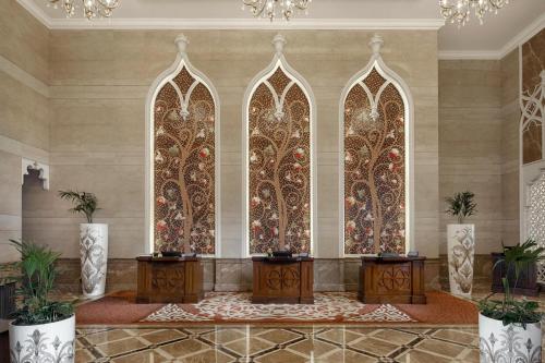 a lobby with two tables and stained glass windows at Marsa Malaz Kempinski, The Pearl in Doha