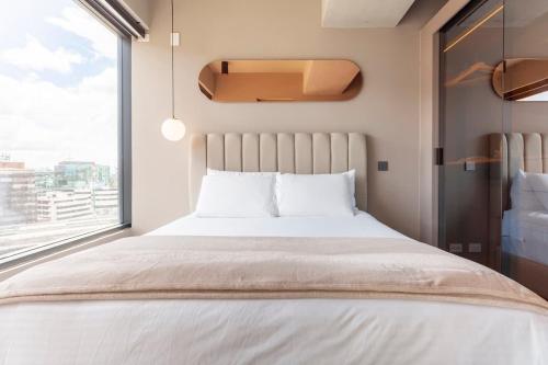 a bedroom with a large bed with a large window at Luxury ultramodern in club house building with poolspa in Bogotá