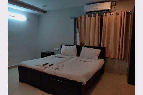 a bed with white sheets and pillows in a room at Collection O Jubilee Banjara Suites in Hyderabad