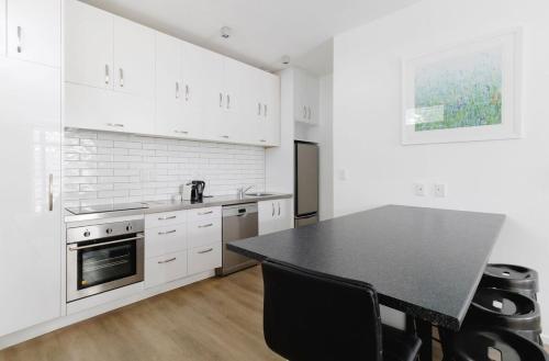 a kitchen with white cabinets and a black counter top at Spacious 3BR Retreat on City Fringe w Free Parking in Wellington