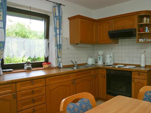 a kitchen with wooden cabinets and a table and a window at Gästehaus Steiger in Bad Birnbach