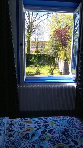 a bedroom with a window looking out at a yard at La Maison Du Bulot in Fruges