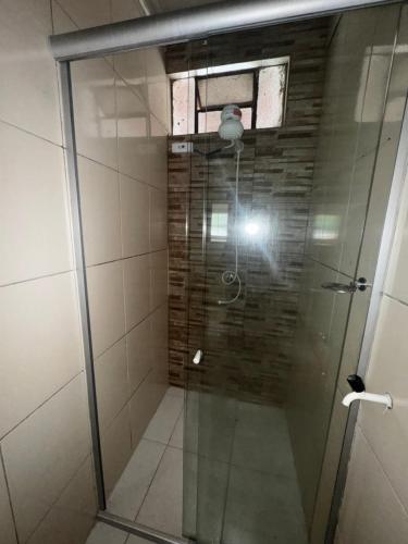 a shower with a glass door and a window at Apartamento no centro da Vila dos cabanos in Barcarena