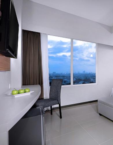 a room with a large window and a table and chair at favehotel Rungkut Surabaya in Surabaya