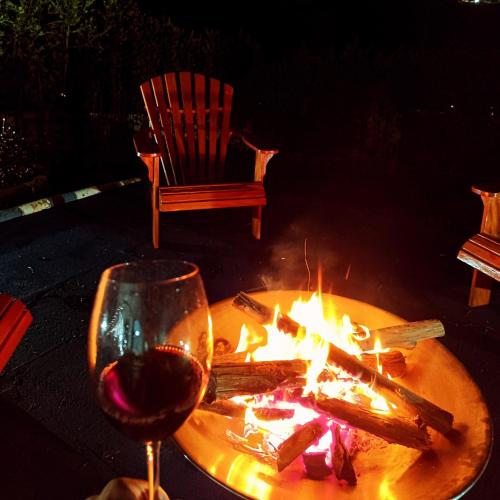 a glass of wine next to a table with a fire at Chácara das Araras in Lindóia