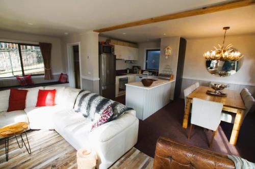 a living room with a white couch and a kitchen at Mountain Retreat Suitable for 2 Families, Sleeps 8 in Mount Buller