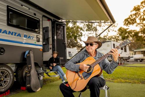 a man playing a guitar next to an rv at Landsborough Holiday Park in Landsborough