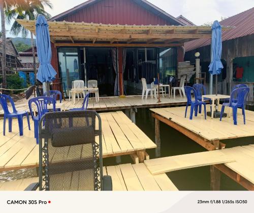 a wooden deck with blue chairs and tables on the water at Ankounamatata in Koh Rong Island