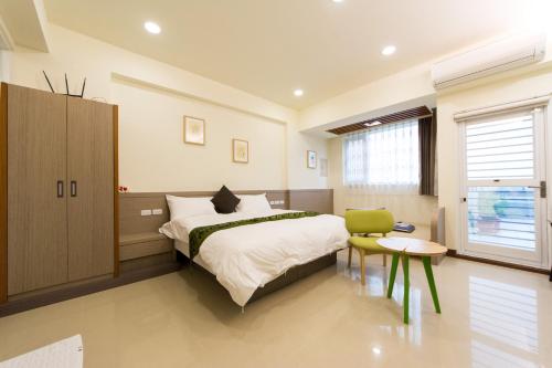 a bedroom with a large bed and a green chair at Jerry B&B in Taitung City