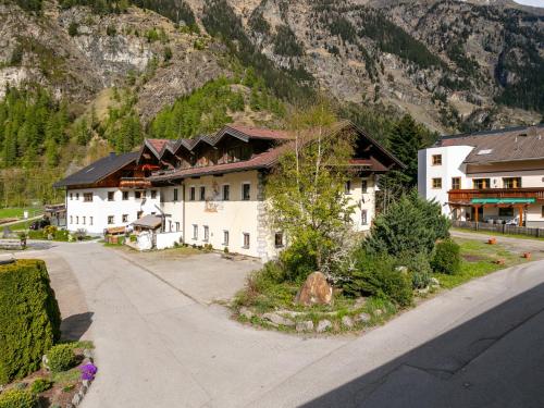 a large white building with a mountain in the background at Schweizerhof Enzian in Huben