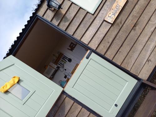 an open garage door on a house with a window at Under the Stars Shepherds Huts at Harbors Lake in Newchurch
