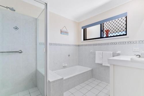 a white bathroom with a tub and a sink at Tweed Escape in Tweed Heads
