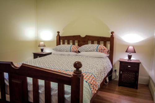 1 dormitorio con 1 cama de madera y 2 mesitas de noche en Heather's Mica Cottage, en Broken Hill