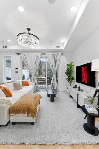 a living room with a white couch and a tv at Luxury 3BR Backyard Oasis Close to NYC FirePit in Jersey City