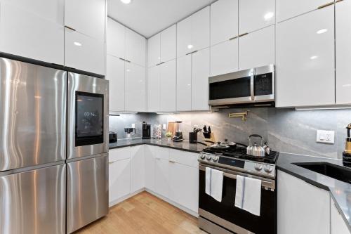 a kitchen with white cabinets and a stainless steel refrigerator at Luxury 3BR Backyard Oasis Close to NYC FirePit in Jersey City
