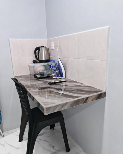 a kitchen counter with a table and a chair at Cms Roomstay Alor Setar in Alor Setar