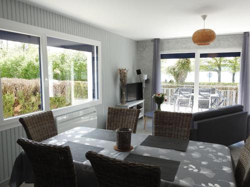 une salle à manger avec une table, des chaises et des fenêtres dans l'établissement Gîte au bord du lac avec terrasse, idéal pour la famille - FR-1-611A-17, à Villegusien Le Lac