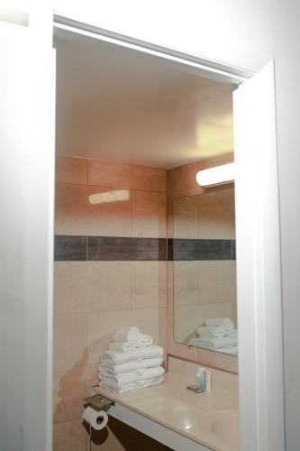 a bathroom with a mirror and a sink and towels at Southern Breeze Ocean Front Hotel in Myrtle Beach