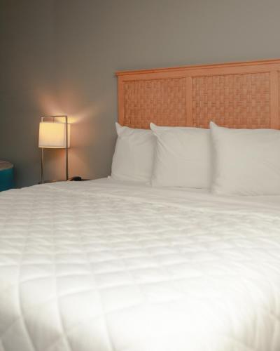 a large bed with white sheets and pillows at Southern Breeze Ocean Front Hotel in Myrtle Beach