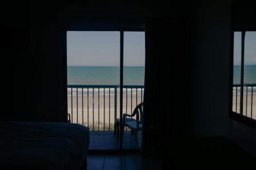 a bedroom with a view of the ocean from a balcony at Southern Breeze Ocean Front Hotel in Myrtle Beach