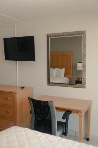 a bedroom with a desk and a mirror and a bed at Southern Breeze Ocean Front Hotel in Myrtle Beach