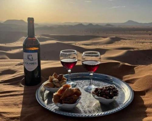 un piatto di cibo e due bicchieri di vino nel deserto di Luxurious Dream Camp a Merzouga