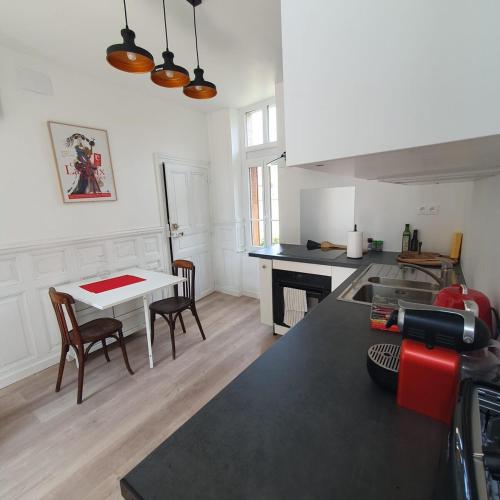 une cuisine avec un comptoir et une table avec des chaises dans l'établissement Maison la Paroisse, proche des Thermes, à Bourbon-lʼArchambault