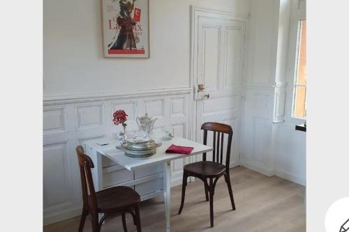 a dining room with a white table and two chairs at Les Demeures du Parc, La Paroisse, proche des Thermes in Bourbon-lʼArchambault