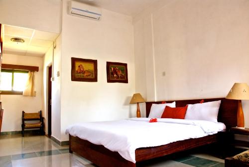 a bedroom with a bed with white sheets and red pillows at Galu Inn in Diani Beach