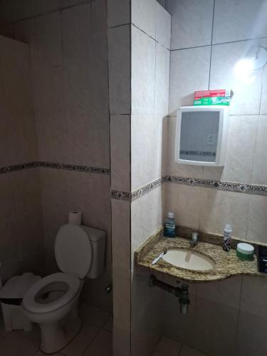 a bathroom with a toilet and a tv on the wall at Casa espaçosa bem localizada in Belém