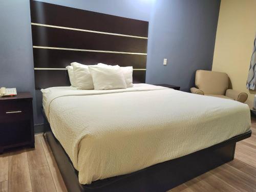 a bedroom with a large bed and a chair at Days Inn by Wyndham Baton Rouge Airport in Baton Rouge