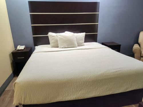 a bedroom with a white bed with two pillows at Days Inn by Wyndham Baton Rouge Airport in Baton Rouge