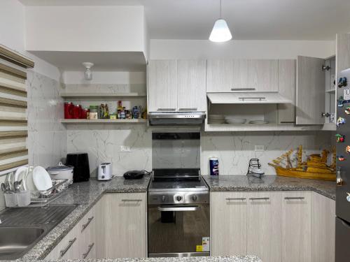 a kitchen with stainless steel appliances and white cabinets at Casa de ensueño, con vista al Mar in Manta