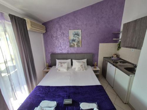 a small bedroom with a bed and a purple wall at Apartmani Villa Anita in Neum