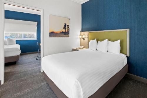 a hotel room with a large white bed and blue walls at SureStay Hotel by Best Western Santa Monica in Los Angeles
