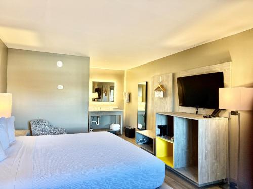 a hotel room with a bed and a flat screen tv at Days Inn by Wyndham Kenner/New Orleans Airport South in Kenner