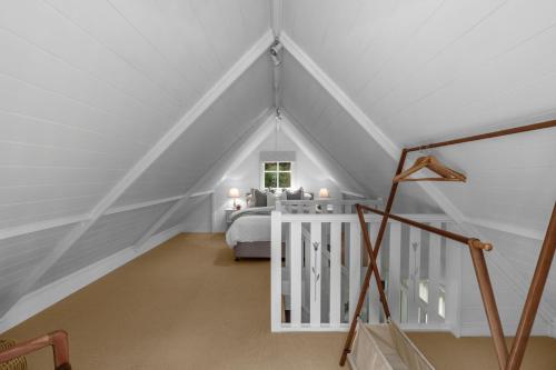 - une chambre mansardée blanche avec un lit et une fenêtre dans l'établissement Eco Cottage Alpine Southern Highlands, à Alpine